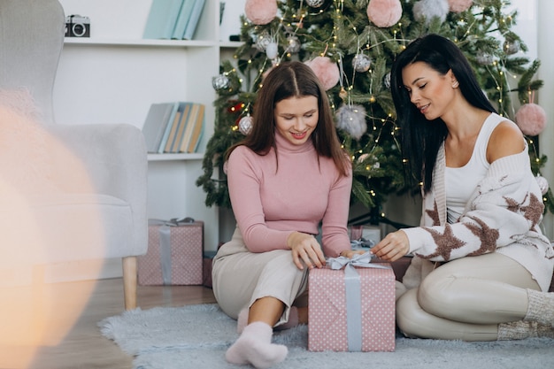 Madre con la figlia adulta con i regali di Natale dall'albero di Natale