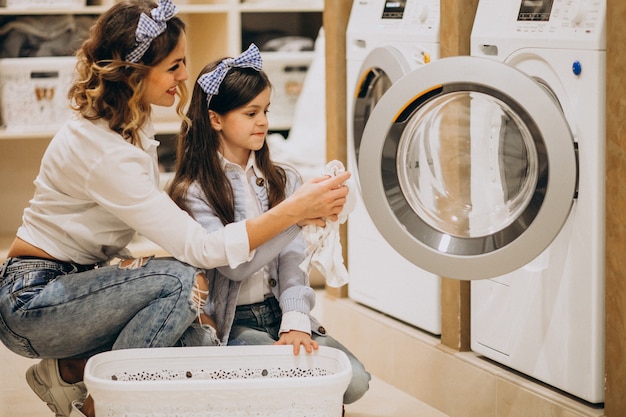Madre con la figlia che fa lavanderia alla lavanderia automatica del self service