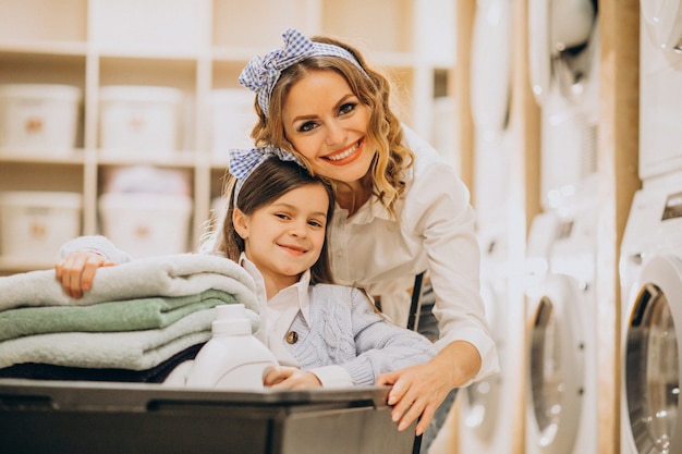 Madre con la figlia che fa lavanderia alla lavanderia automatica del self service