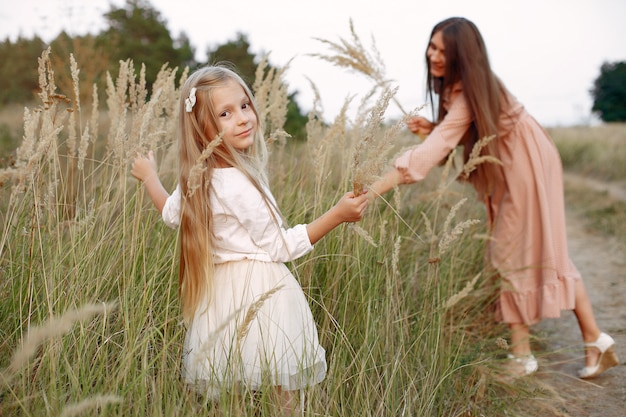 Madre con la figlia che gioca in un campo di autunno