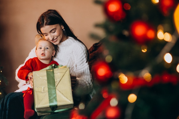 Madre con la figlia che si siede dall'albero di Natale