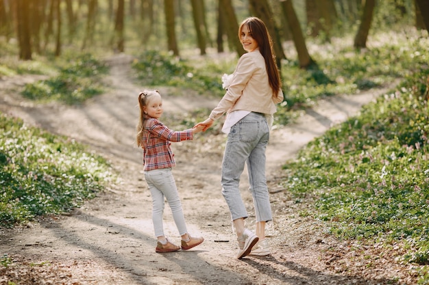 Madre con la figlia in una foresta di primavera con il cane