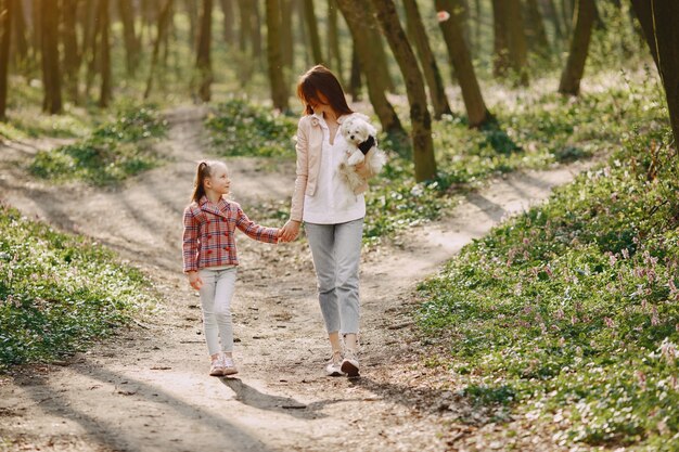 Madre con la figlia in una foresta di primavera con il cane