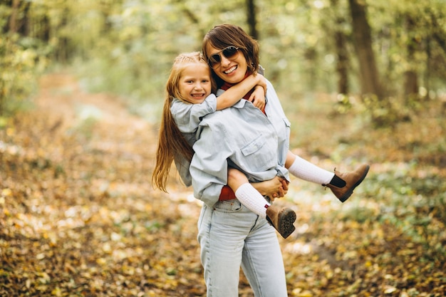 Madre con la figlia piccola nella foresta piena di foglie d'oro