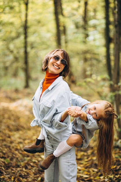 Madre con la figlia piccola nella foresta piena di foglie d'oro