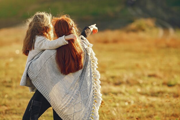 Madre con la piccola figlia che gioca in un campo di autunno