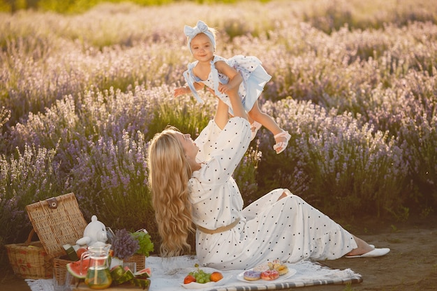 Madre con la piccola figlia sul campo di lavanda. Bella donna e bambino sveglio che giocano nel campo del prato. Vacanze in famiglia in una giornata estiva.