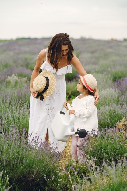 Madre con la piccola figlia sul campo di lavanda. Bella donna e bambino sveglio che giocano nel campo del prato. Vacanze in famiglia in una giornata estiva.