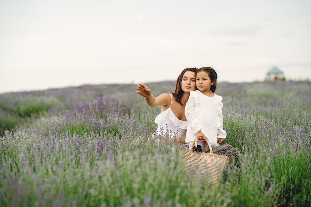 Madre con la piccola figlia sul campo di lavanda. Bella donna e bambino sveglio che giocano nel campo del prato. Vacanze in famiglia in una giornata estiva.