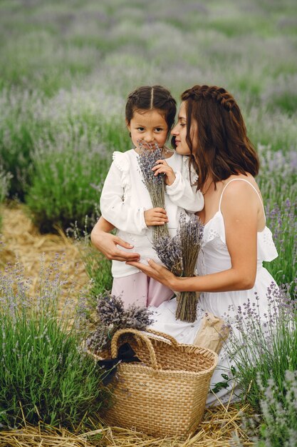 Madre con la piccola figlia sul campo di lavanda. Bella donna e bambino sveglio che giocano nel campo del prato. Vacanze in famiglia in una giornata estiva.