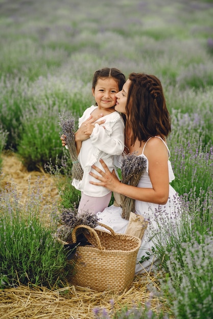 Madre con la piccola figlia sul campo di lavanda. Bella donna e bambino sveglio che giocano nel campo del prato. Vacanze in famiglia in una giornata estiva.