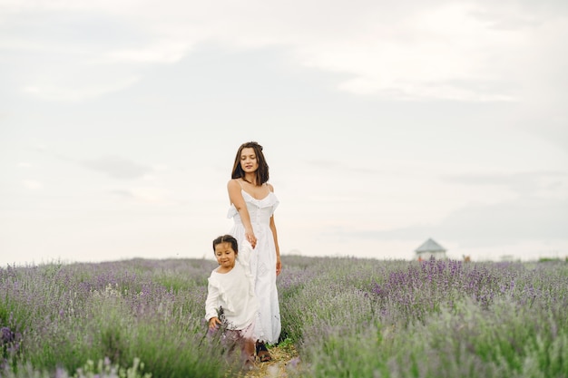 Madre con la piccola figlia sul campo di lavanda. Bella donna e bambino sveglio che giocano nel campo del prato. Vacanze in famiglia in una giornata estiva.