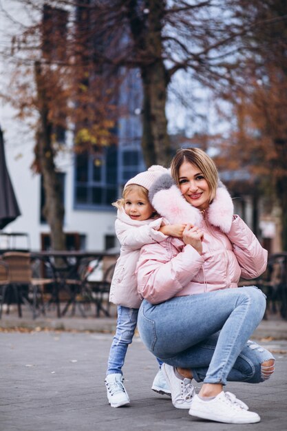 Madre con la sua piccola figlia vestita in panno caldo a lato della strada