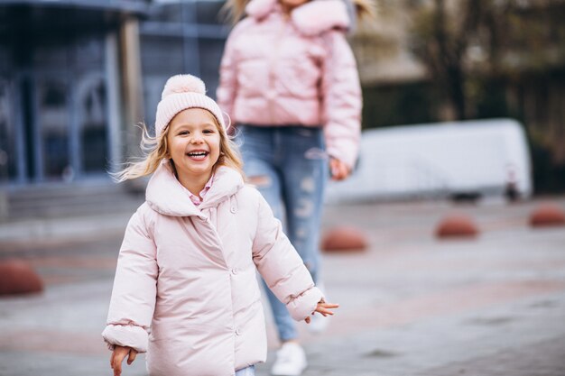 Madre con la sua piccola figlia vestita in panno caldo a lato della strada