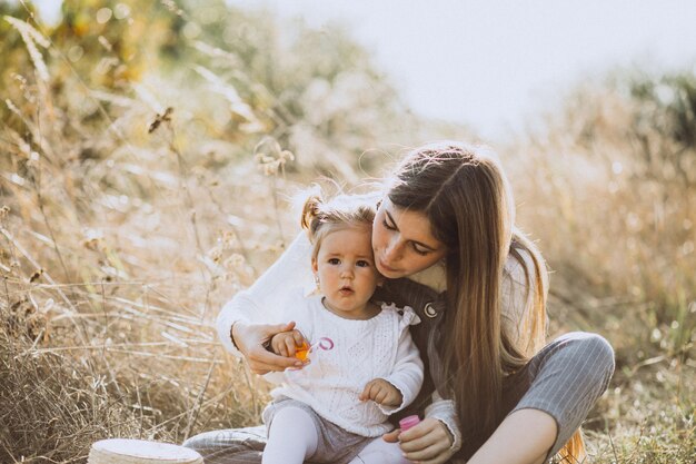 Madre con le bolle di sapone di salto della piccola figlia del bambino in parco