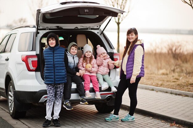 Madre con quattro bambini seduti nel bagagliaio di una grande automobile suv