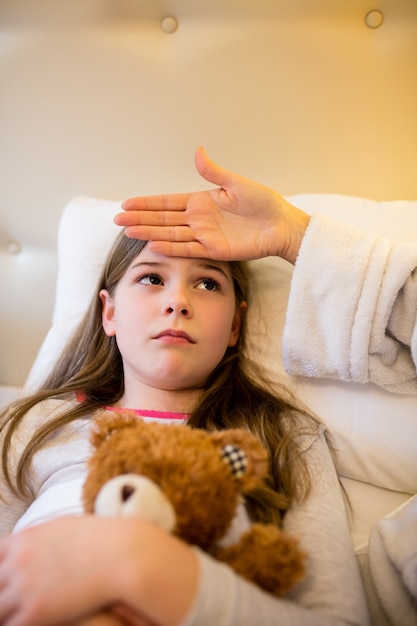 Madre controllando la febbre della figlia in camera da letto