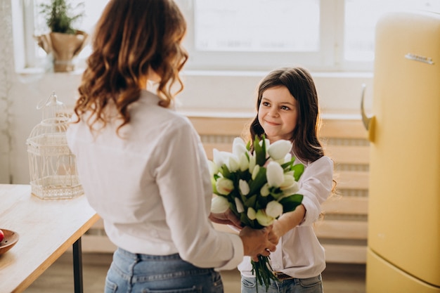 Madre di saluto della bambina con i fiori il giorno di madri