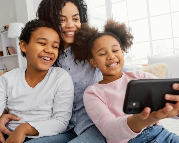 Madre di smiley e bambini che prendono selfie a casa