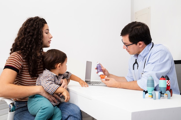 Madre di vista laterale che presta attenzione alla visita di un medico