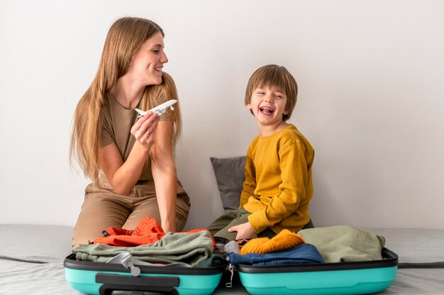 Madre e bambino a casa con figurina di aeroplano e bagagli