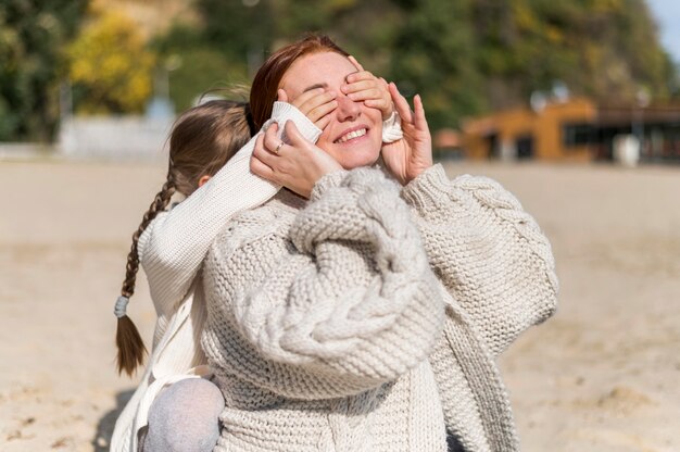 Madre e bambino di smiley del colpo medio alla spiaggia