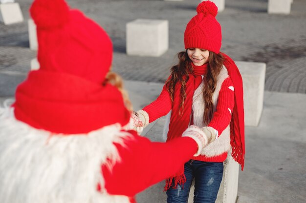 Madre e bambino in cappelli invernali lavorati a maglia in vacanza di Natale in famiglia. Cappello e sciarpa in lana fatti a mano per mamma e bambino. Lavoro a maglia per bambini. Capispalla in maglia. Donna e bambina in un parco.