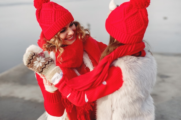 Madre e bambino in cappelli invernali lavorati a maglia in vacanza di Natale in famiglia. Cappello e sciarpa in lana fatti a mano per mamma e bambino. Lavoro a maglia per bambini. Capispalla in maglia. Donna e bambina in un parco.