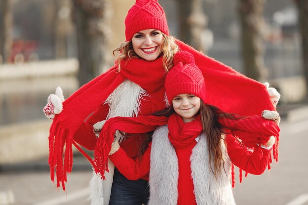 Madre e bambino in cappelli invernali lavorati a maglia in vacanza di Natale in famiglia. Cappello e sciarpa in lana fatti a mano per mamma e bambino. Lavoro a maglia per bambini. Capispalla in maglia. Donna e bambina in un parco.