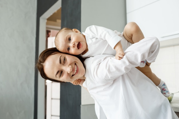 Madre e bambino si divertono, mamma carina porta il bambino sulla schiena