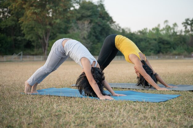 Madre e figlia che fanno yoga. donna e bambino formazione nel parco. sport all'aria aperta. stile di vita sportivo sano, guardare video tutorial online di esercizi di yoga e stretching nell'esercizio del cane rivolto verso il basso