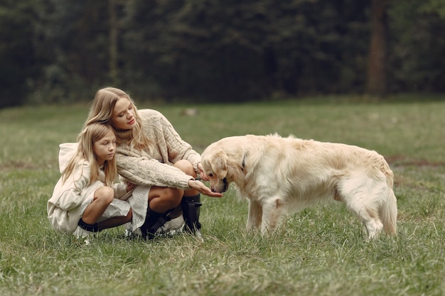 Madre e figlia che giocano con il cane. Famiglia nella sosta di autunno. Pet, animali domestici e concetto di stile di vita