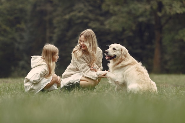 Madre e figlia che giocano con il cane. Famiglia nella sosta di autunno. Pet, animali domestici e concetto di stile di vita