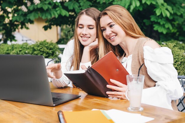 Madre e figlia che guardano nel computer all'esterno.