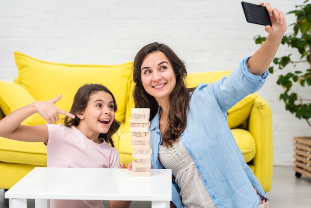 Madre e figlia che prendono un selfie mentre giocano un gioco di torre in legno