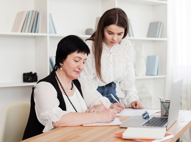 Madre e figlia che scrivono e che per mezzo di un computer portatile