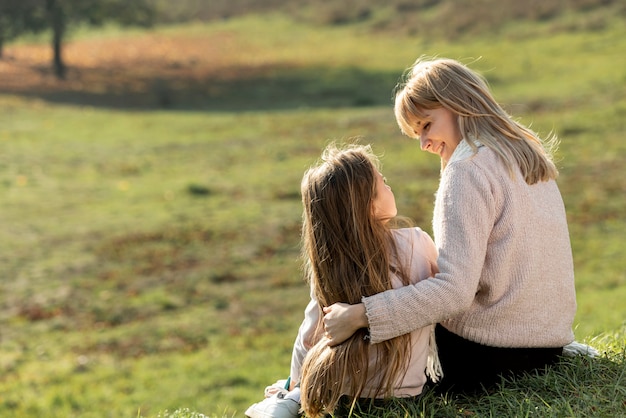 Madre e figlia che si siedono in natura