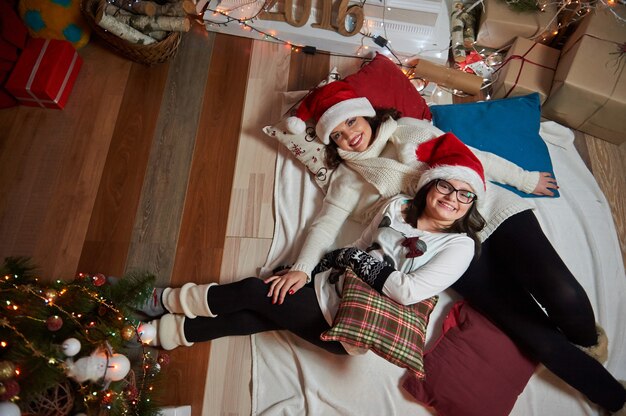 Madre e figlia che si trovano insieme sul pavimento a casa il Natale