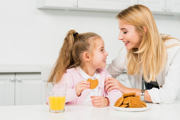 Madre e figlia con biscotti e succo