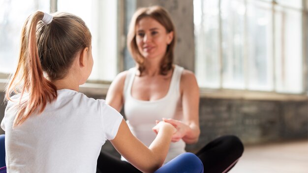 Madre e figlia del primo piano che si tengono per mano sulle stuoie di yoga