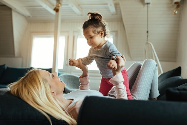 Madre e figlia giocose che si divertono insieme a casa. Il focus è sulla bambina.