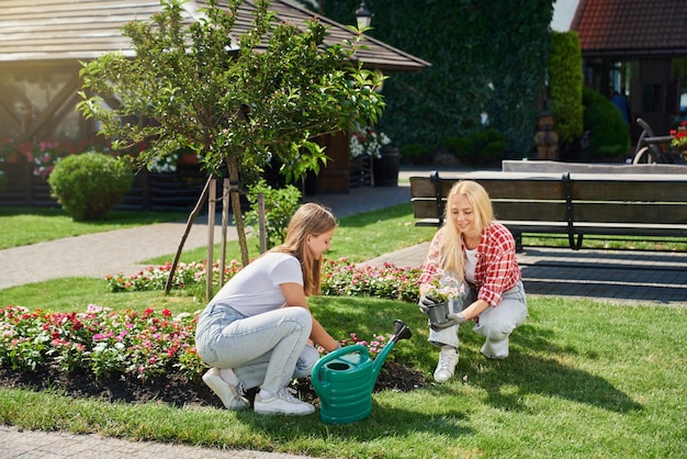 Madre e figlia in guanti che piantano fiori in giardino