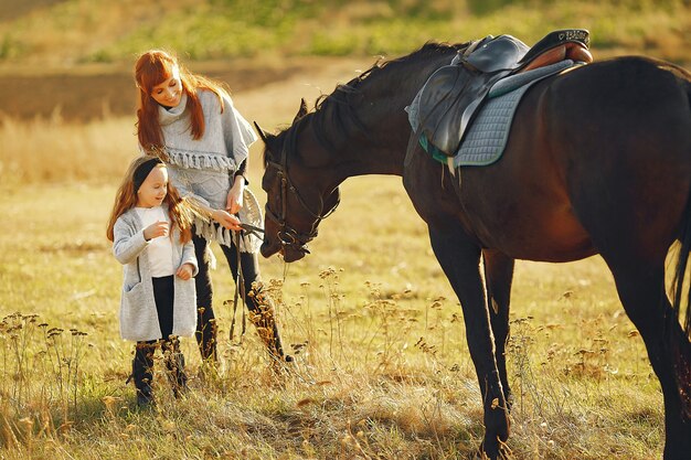 Madre e figlia in un campo che gioca con un cavallo