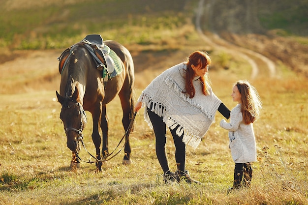 Madre e figlia in un campo che gioca con un cavallo