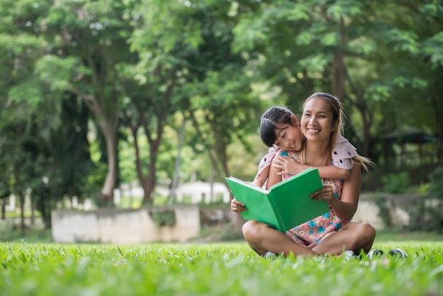 Madre e figlia leggendo una fiaba a sua figlia nel parco