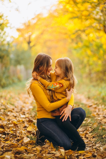 Madre e figlia nel parco pieno di foglie