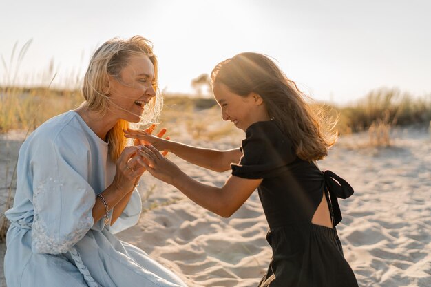 Madre e figlia si divertono sulla spiaggia Colori caldi del tramonto