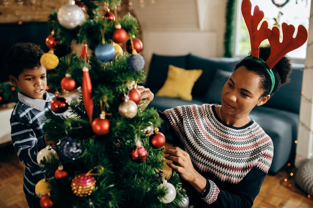 Madre e figlio afroamericani che decorano l'albero di Natale a casa