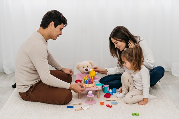 Madre e padre che giocano con la figlia a casa