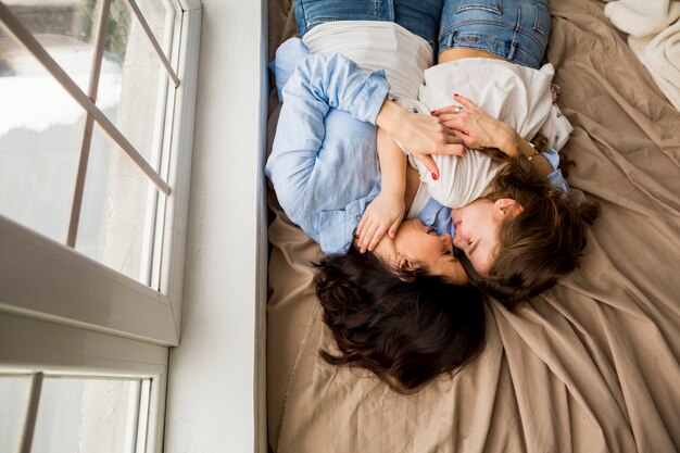 Madre e piccola figlia che abbracciano sul letto